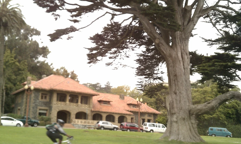 a person is riding a bicycle past a large house