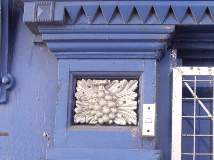 the front door of a blue building has flower designs on it