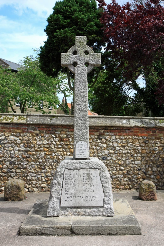 a large stone cross on a memorial on the side of a road