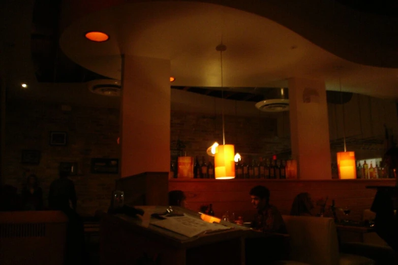 two people sit at a bar and eat in the dark