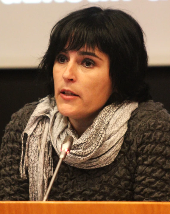 a woman in a black sweater sits at a podium