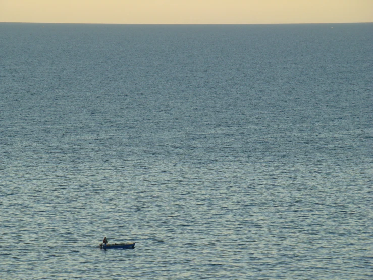 a person on a small boat with the sun setting