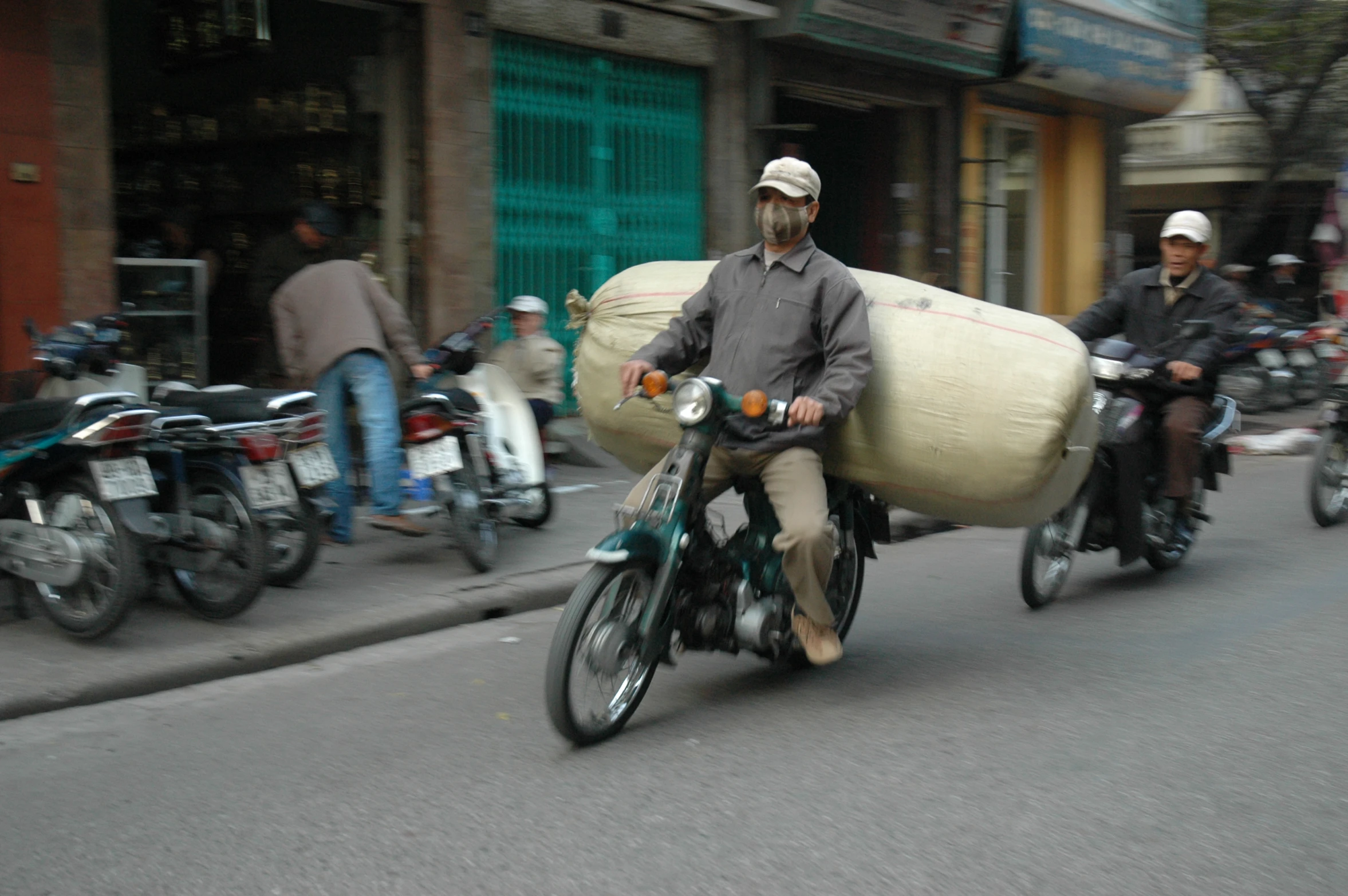 two men on motorcycles carrying goods and bags down the road