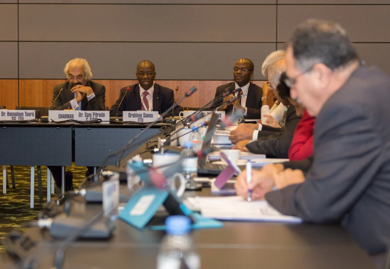 five people sitting at table with papers and a microphone