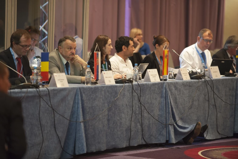 many people are sitting at a long table and using laptops