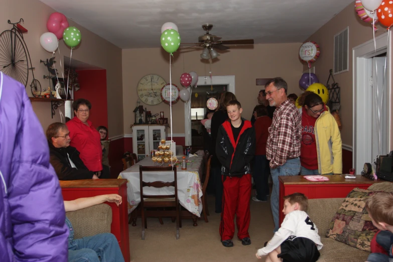 some people standing in a living room with balloons on the ceiling
