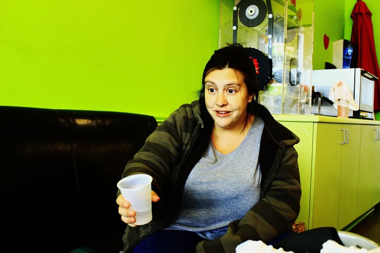 a girl in grey shirt holding up cup