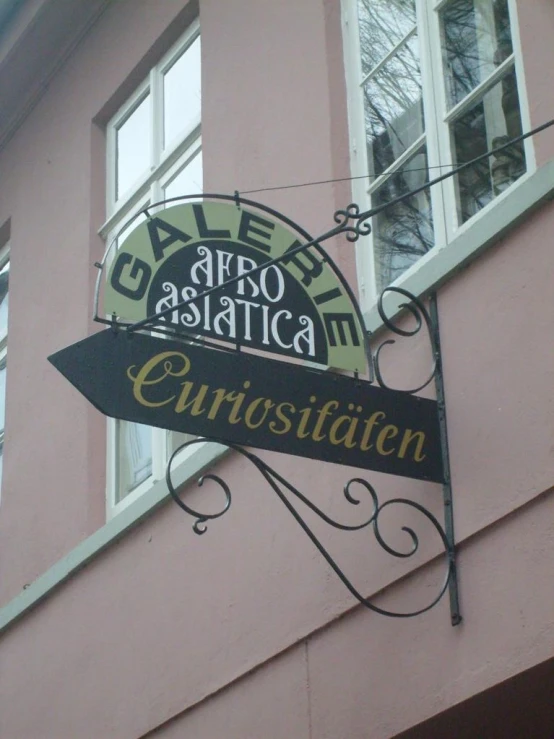 the sign for cafe astragasticata enquisitaton hangs from a pink building