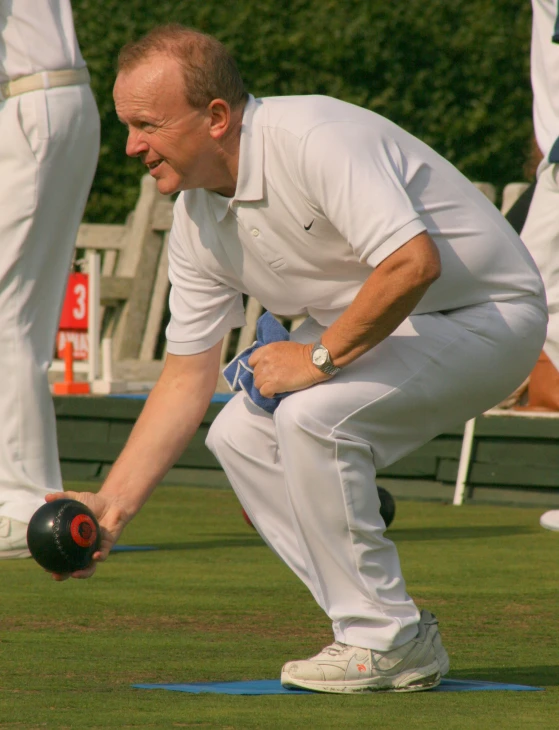 man bowling on grass with his foot on a ball