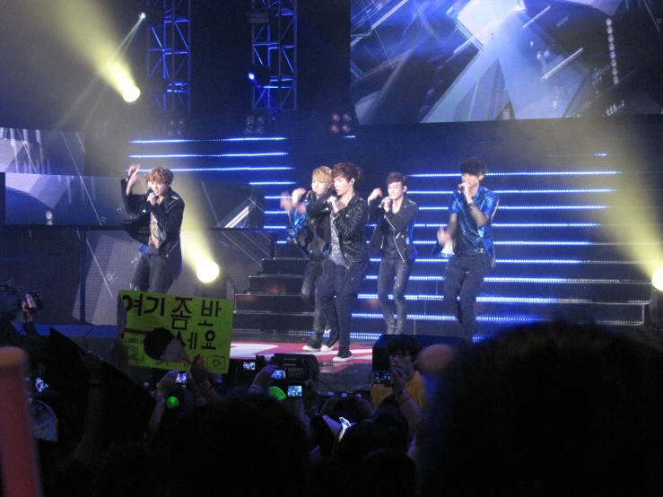 a group of young men stand on stage with their backs turned away