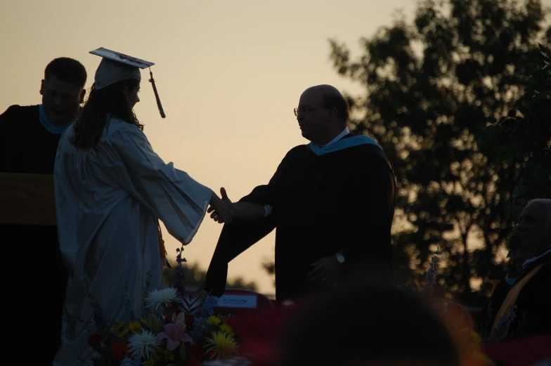 a couple standing next to each other with a graduate's hand in their other's pocket