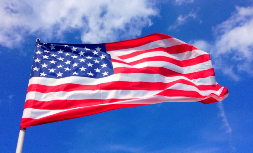 a waving flag on a pole and blue sky with clouds