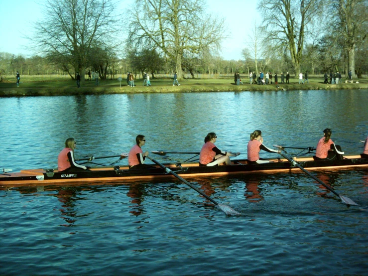 four women in pink shirts paddling a large boat