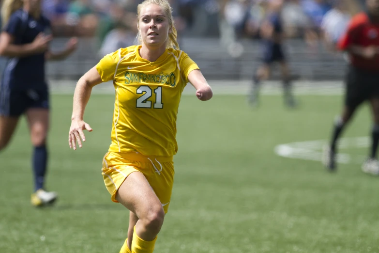 a female soccer player running towards a ball in mid flight