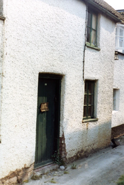 a small, rundown building with a doorway and green door