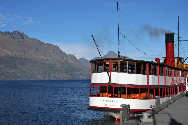 an old boat docked at a marina near a mountain range