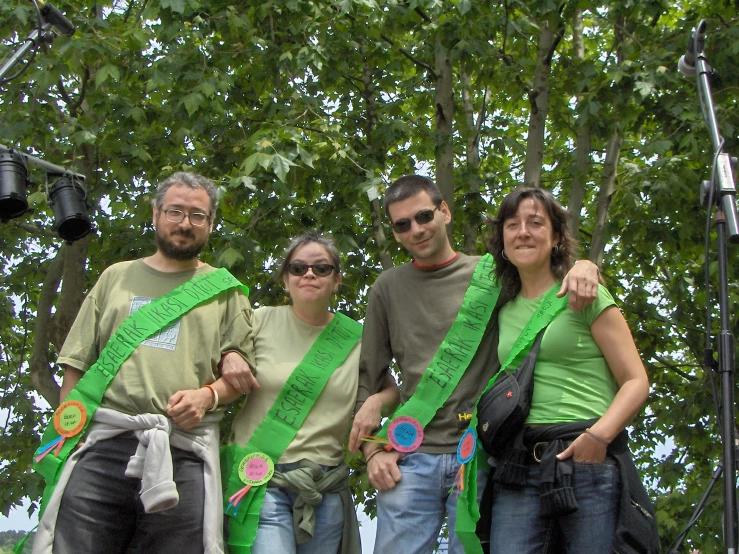 two women, a man and a boy are standing together and wearing green ribbons