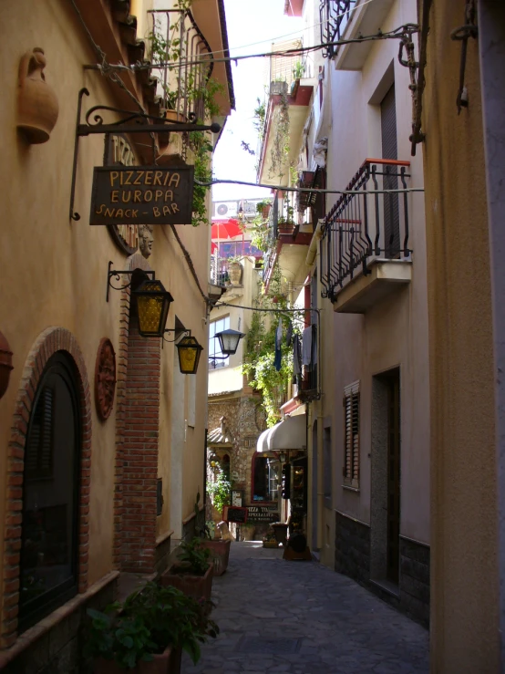 an alleyway with flowers and plants hanging from the walls