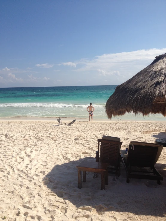 two lawn chairs sitting on a sandy beach