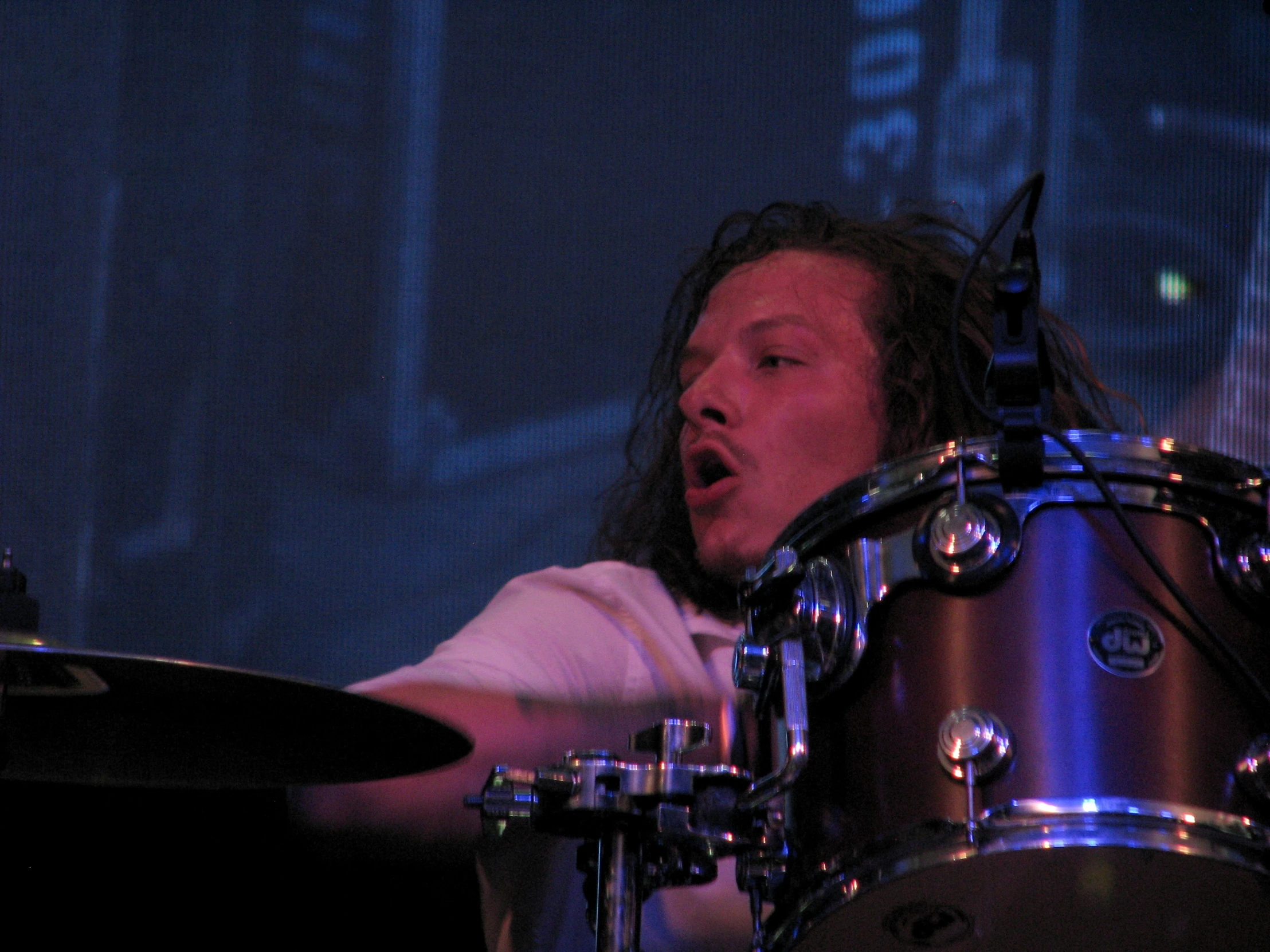 a man with long hair playing a drumset