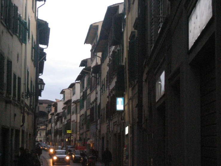 cars drive down a narrow street next to brick buildings
