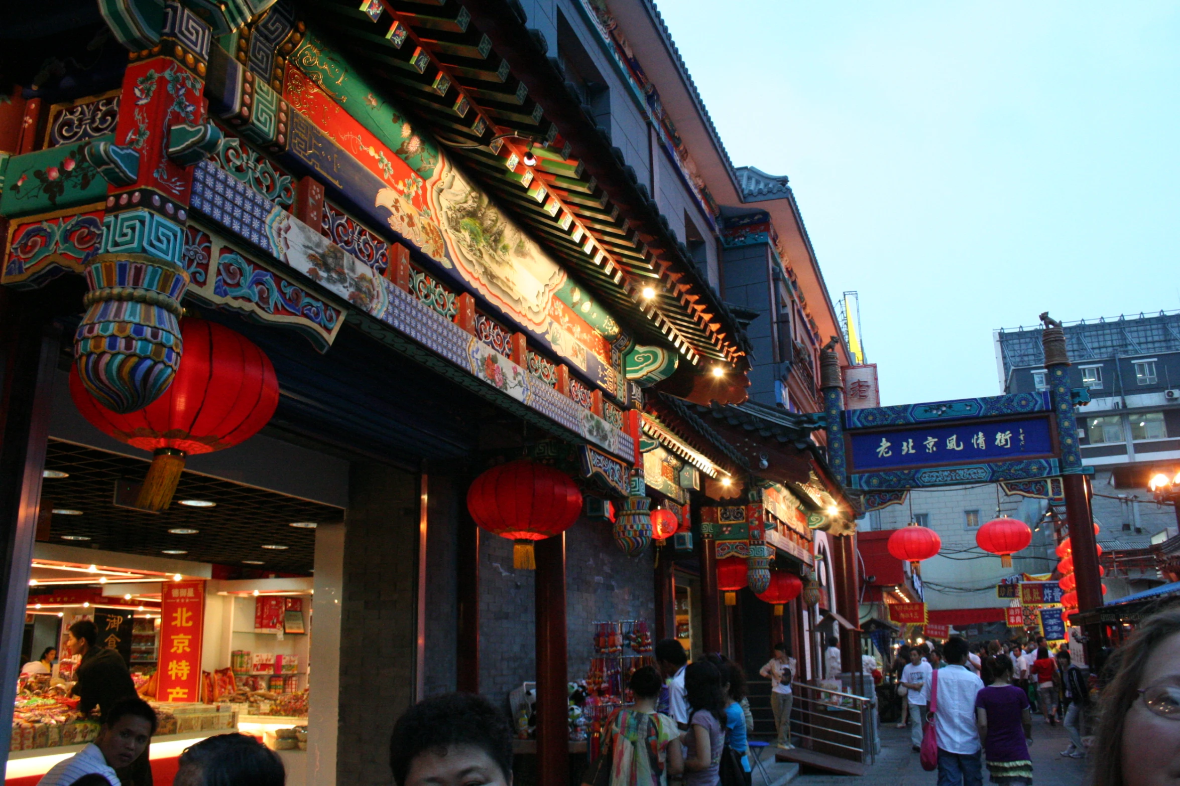 people walk outside in front of stores with lanterns