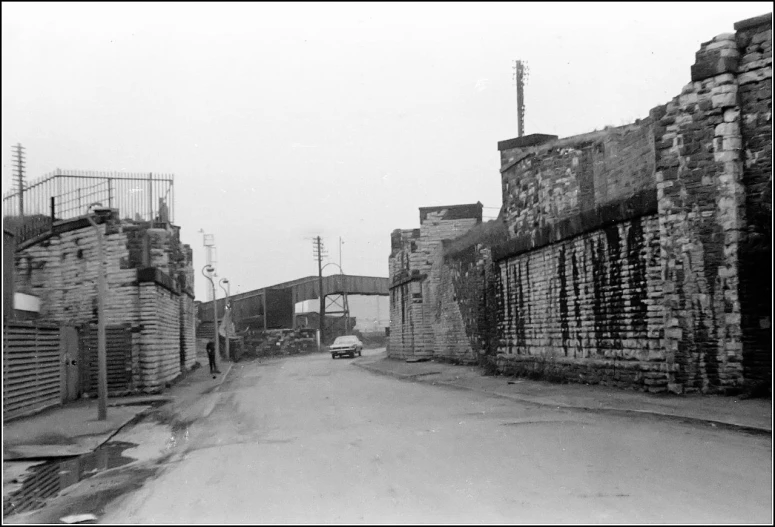 a street in an industrial area with brick walls and a gate