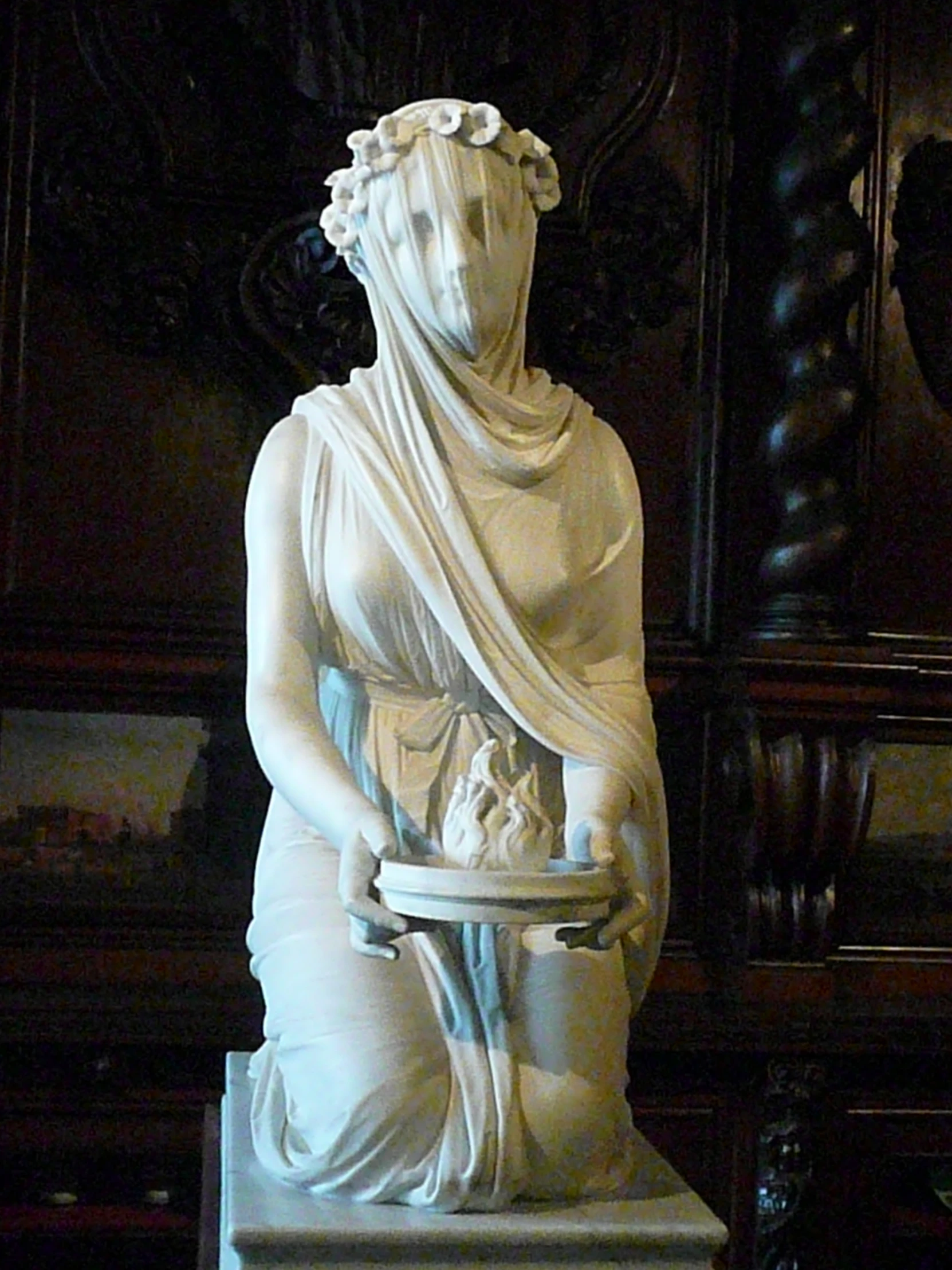 a white statue with a flower in her hair