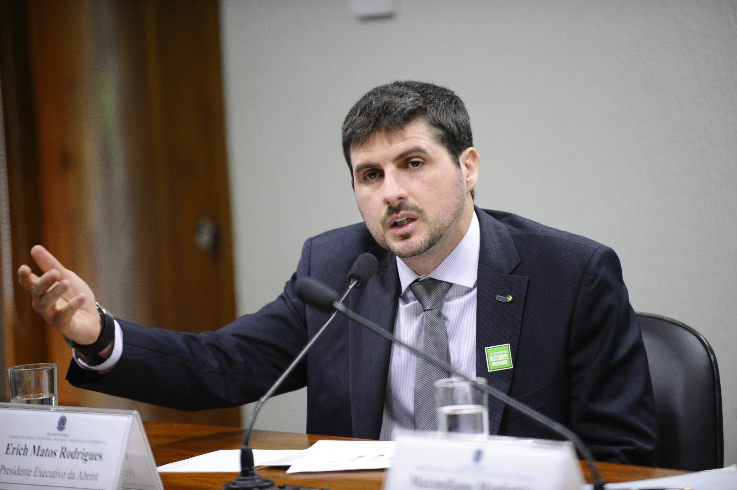 a man sits at a table with microphone in front of him