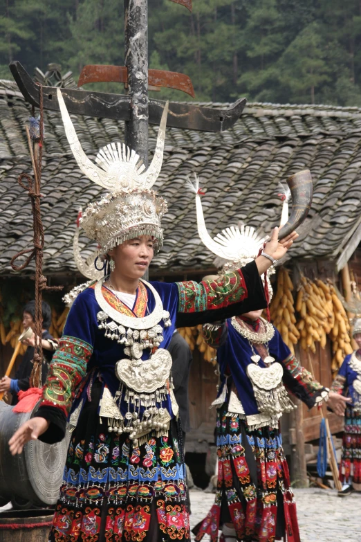 two women in traditional costumes are holding onto umbrellas