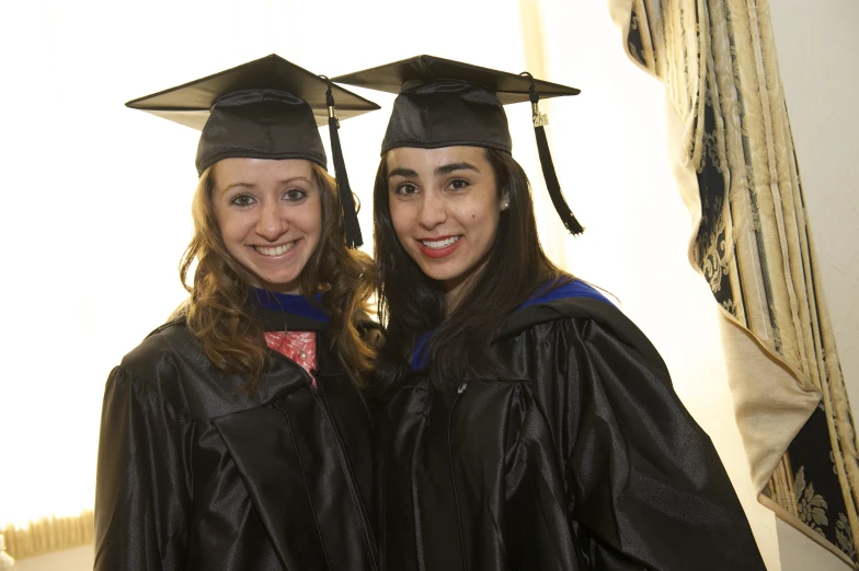 two young women in graduation gowns posing for the camera