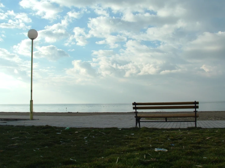 a wooden bench sits on the beach next to an empty park