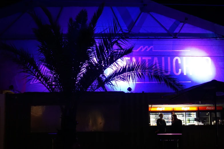 an outside view of a building at night, with people sitting on chairs