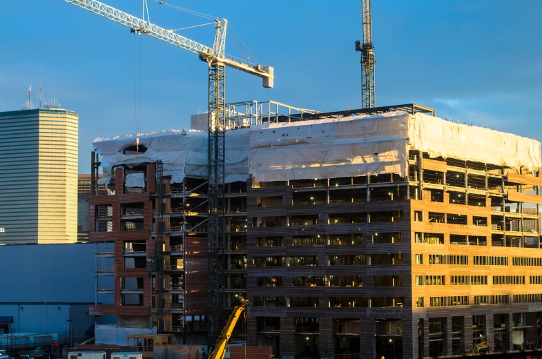 the building is surrounded by construction cranes on top of it