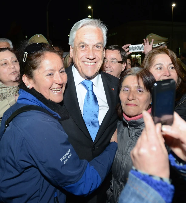 a smiling man taking a selfie with people behind him