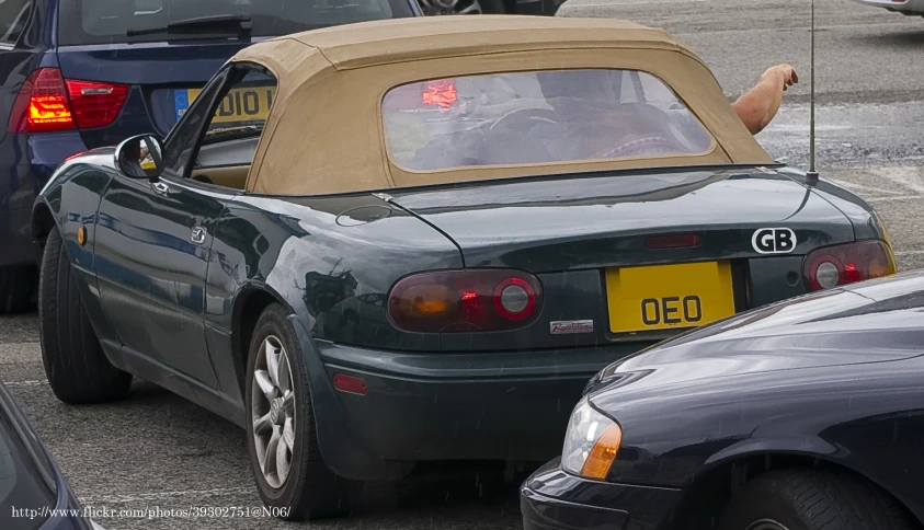 a car is in a lot, with a large object sticking out the back window