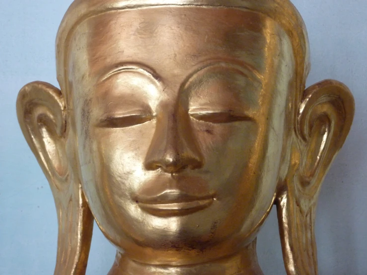 the head of an old, gold painted buddha statue