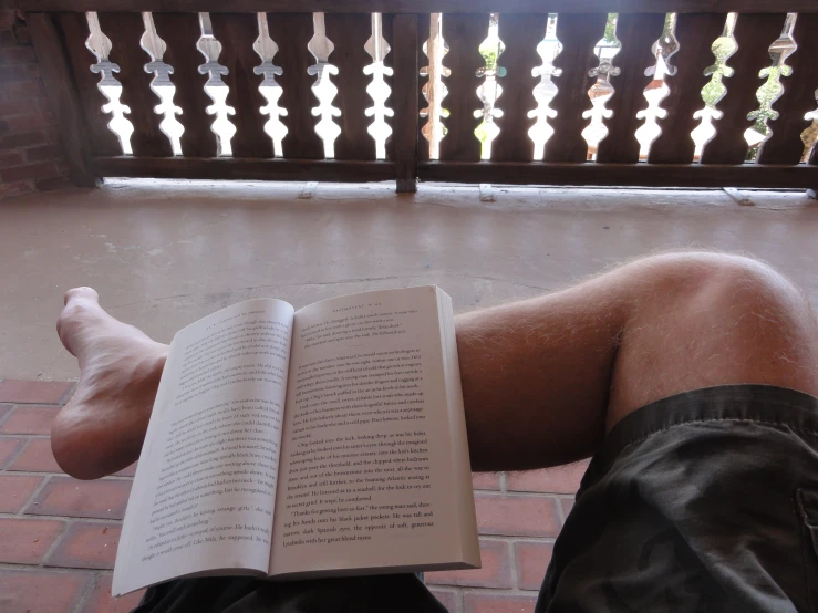 the man is reading his book by the railing