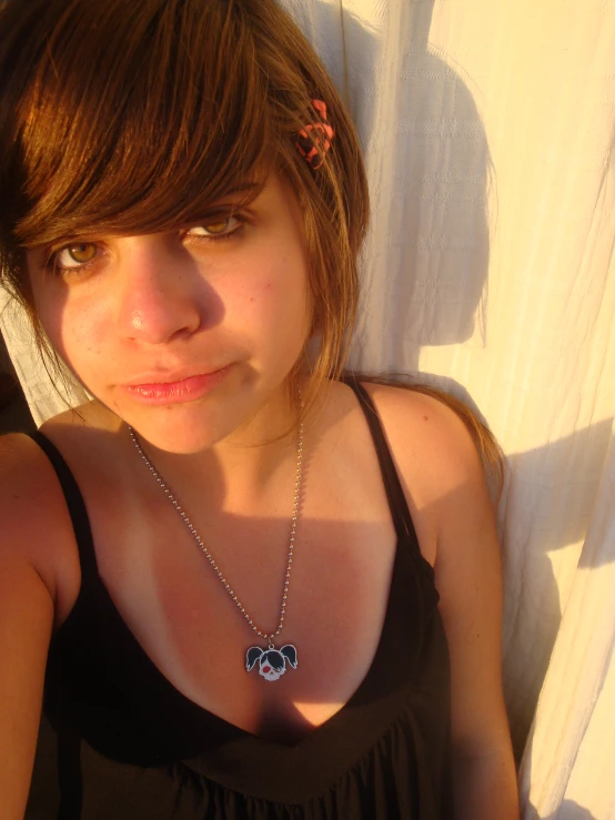 a girl with brown hair wearing a necklace and smiling