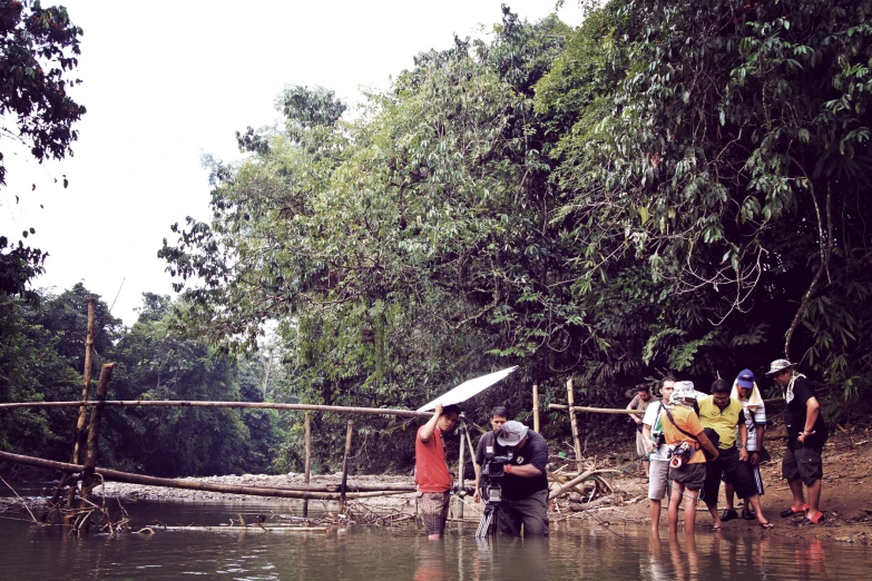 a group of people standing in water, with an umbrella