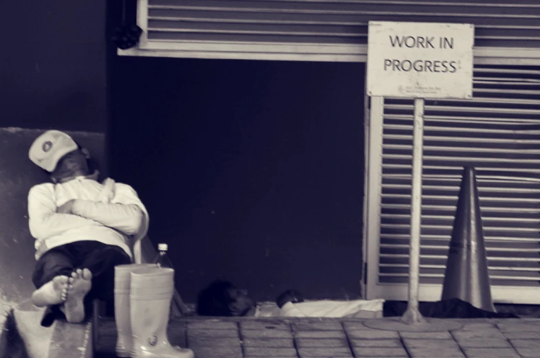 a man sitting on the bench with a sign that says work in progress