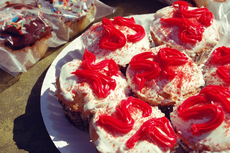 a plate topped with lots of frosted cupcakes