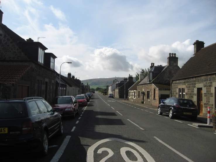 a quiet street with cars parked on the sidewalks