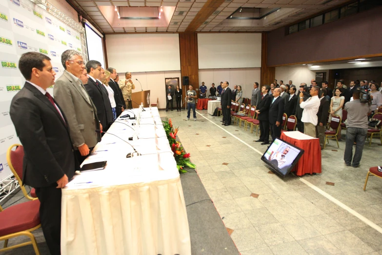 several men standing at tables, waiting for the event to begin