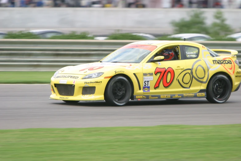 a yellow modified car driving down a race track