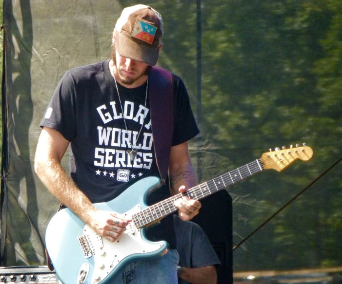 a man plays guitar and sings with microphones behind him