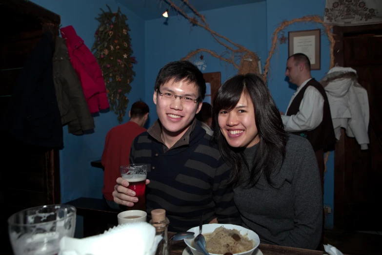 two people are smiling for the camera at a restaurant