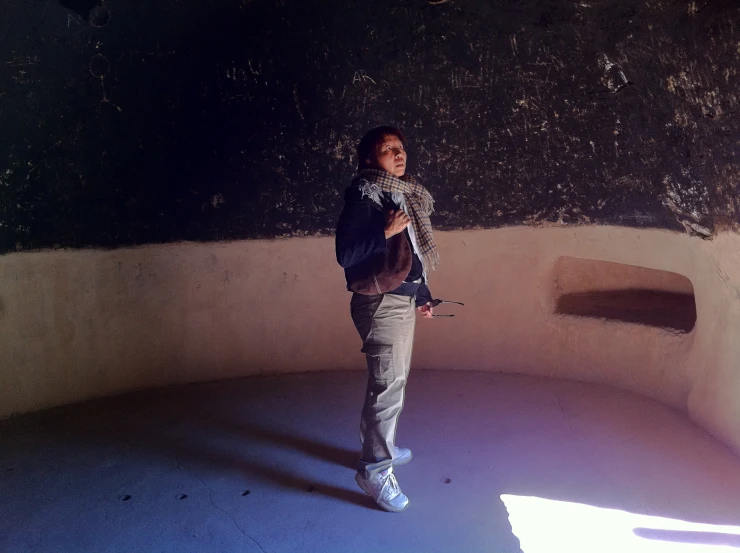 a person wearing a hat and scarf standing inside an indoor stone