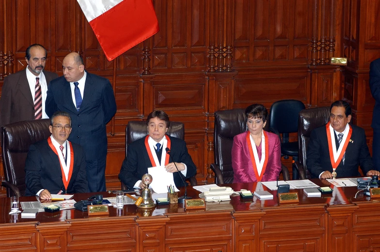 four people in suits sit at a desk