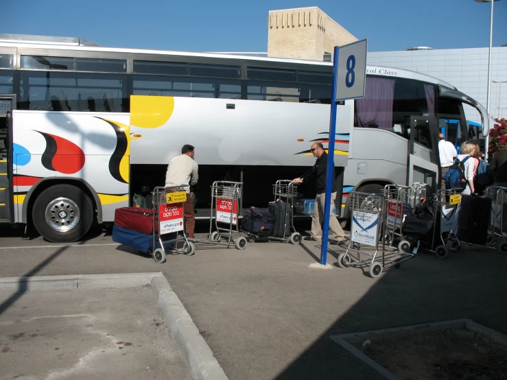 several people hing carts up to a colorful bus